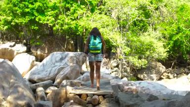 背着背包的女人在河上的桥上行走，在山上爬山。 流浪妇女在停尸间行走